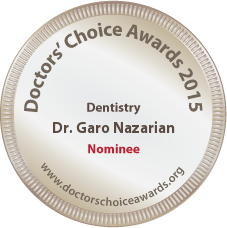 The image shows a circular badge with text and symbols on it. The badge features the year 2015 prominently at the top, followed by the words Doctor s Choice Awards. Below this title, there is a name Dr. Goro Nazarian, and underneath that, there is a profession listed as Dentist. At the bottom of the badge, it reads Nominee in capital letters. The text on the badge is clear and legible. In the center of the badge, there is an emblem with a shield and a crown above it. The background of the badge is white, and the border is a thin gold line. The overall style of the image is formal and professional, suggesting that the badge represents recognition or an award in the field of dentistry.
