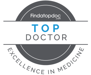 The image shows a logo with text that reads TOP DOCTOR above a circular emblem featuring a stethoscope, and below that, additional text states FINDATOPDOC followed by EXCELLENCE IN MEDICINE.